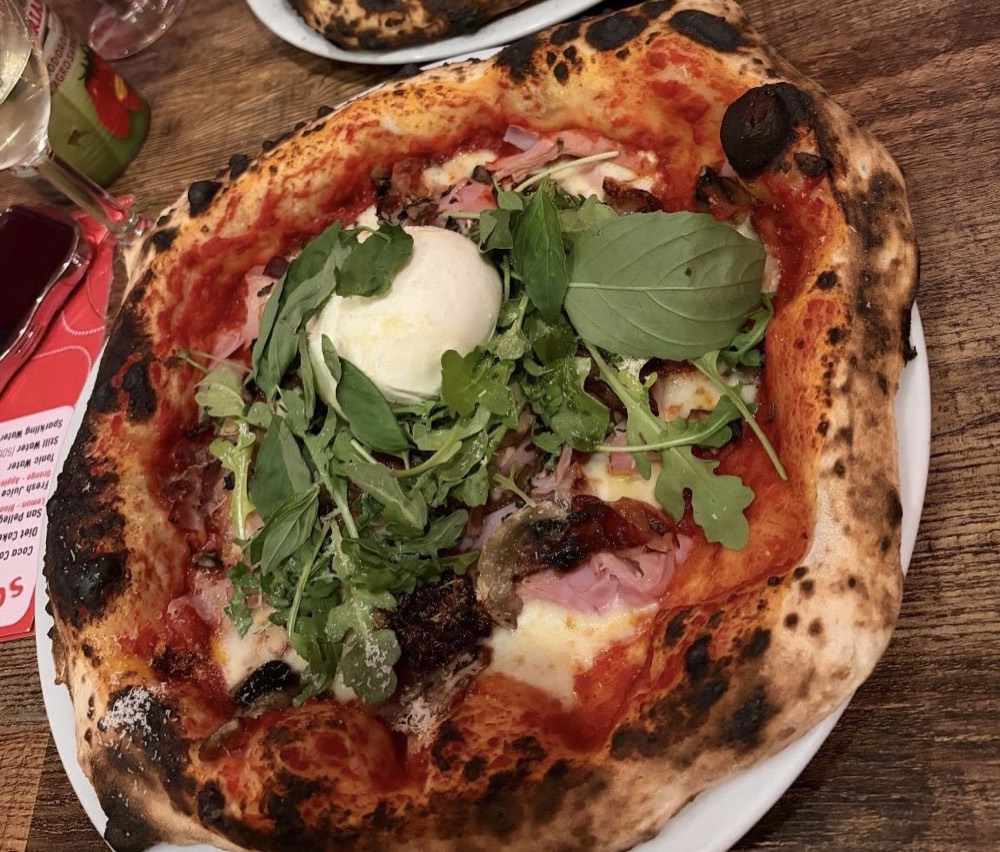 A Ciaooo pizza topped with burrata, rocket and basil, its sourdough crust blistered from the oven.